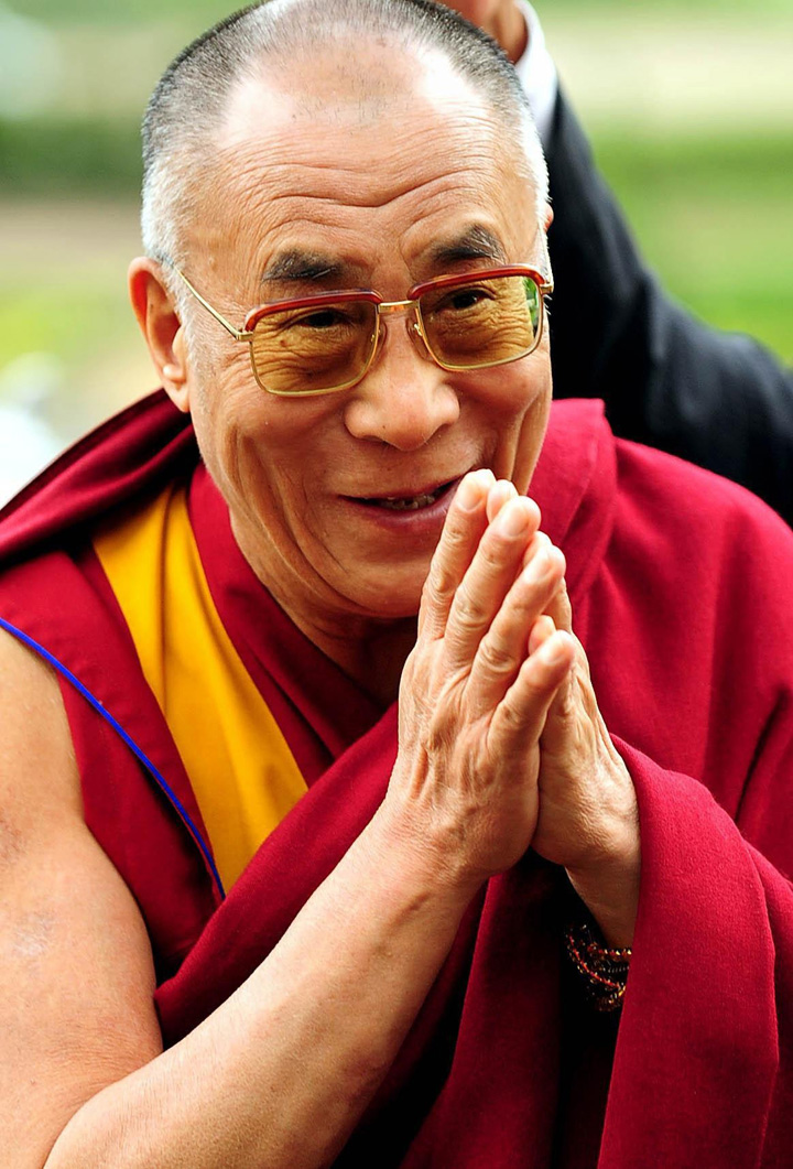 Le Dalaï Lama, les mains en prières, souriant 